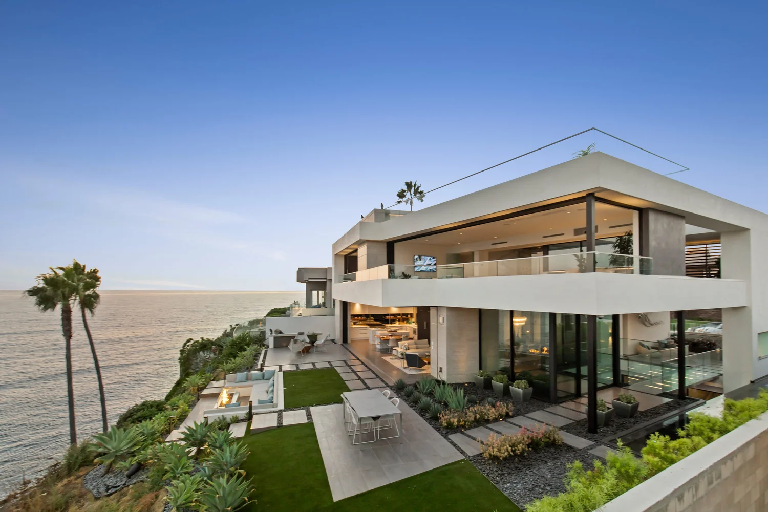 White oceanfront home with glass balconies, landscaped terraces and palms in La Jolla